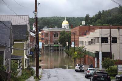 The golden dome of the Vermont Statehouse rises over a flooded street in downtown Montpelier on July 11. Summer flooding caused damage to downtown, and the federal building that housed the local post office. (Mike Dougherty/Vermont Public)