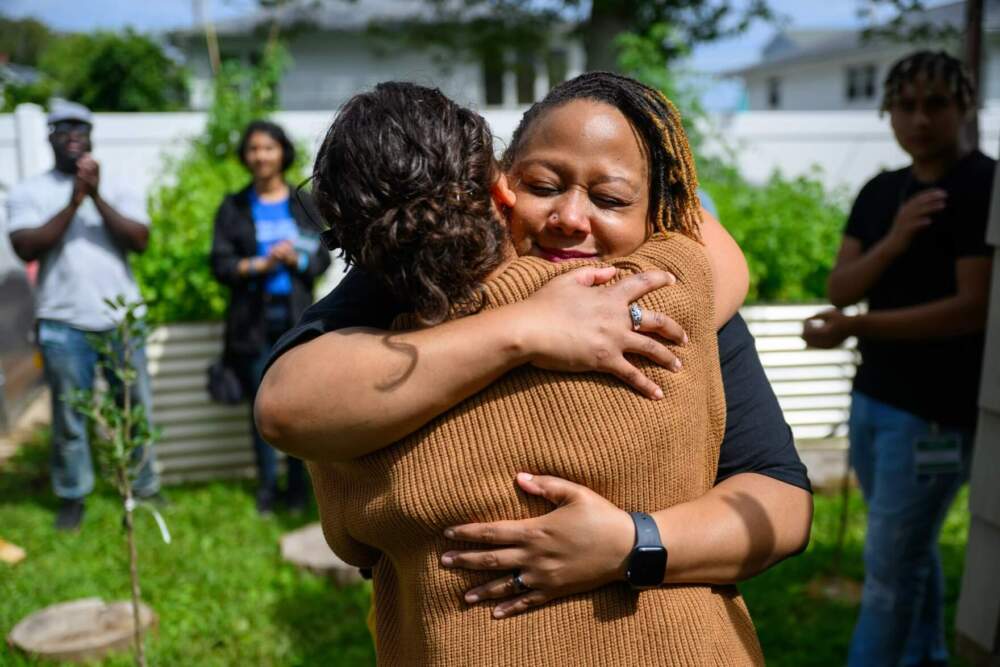 East Haven resident Dr. Ivette Ruiz embraces her friend Crystal Jeter-Prince at the grand opening of Healing By Growing Farms, a space that Ruiz created at her home to give trauma survivors access to nature and therapeutic farming. (Ryan Caron King/Connecticut Public)