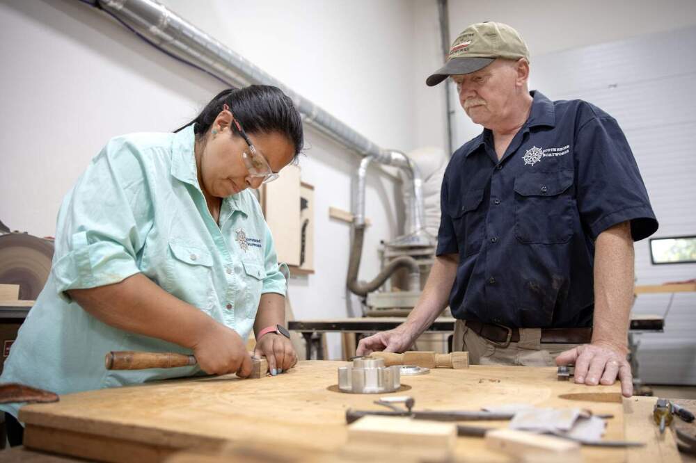 Christina Fuller and her father Bob work on a bench at their workshop at South Shore Boatworks in Carver, Mass. (Robin Lubbock/WBUR)