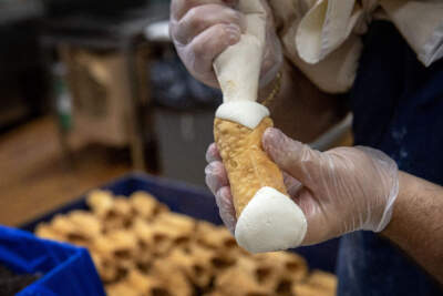 A baker fills a cannoli in the kitchen of Mike's Pastry in Boston's North End. (Robin Lubbock/WBUR)