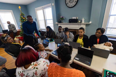 Huguens Altidor leads a computer skills class with a group migrants recently taken in by the Bethel AME Church rectory in Jamaica Plain. (Jesse Costa/WBUR)