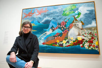 Artist Dinora Justice sits with her legs crossed in front of her painting, Portrait 60, after Titian's &quot;The Rape of Europa&quot;. It depicts a silhouette of a women laying over a white bull surrounded by a body of water.