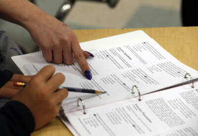 A teacher points on a student's worksheet as she teaches a test preparation class. (Alex Brandon/AP)
