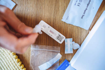 A woman squeezing the sample liquid on a test strip while carrying out a Covid-19 rapid self test at home. (Getty Images)