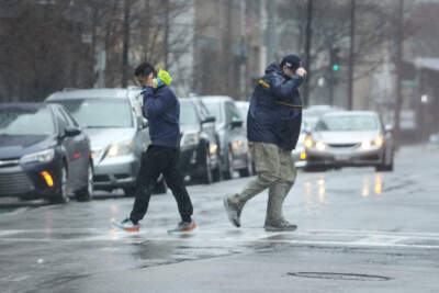 Passers-by are buffeted by wind as they cross a street, Monday, Dec. 18, 2023, in Boston. (Steven Senne/AP)