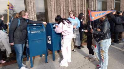 A student places an envelope in a mailbox in Springfield Renaissance School's &quot;college march.&quot; (Jill Kaufman/NEPM)