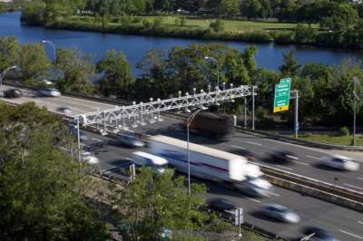 Trucks and automobiles travel under a toll gantry on the Massachusetts Turnpike. (Jesse Costa/WBUR)
