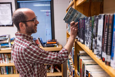 Brian Stokes, acting Library Director at Falmouth Public Library, returns the book “The Boy in the Striped Pajamas” back onto the shelves at the library room at Barnstable County Correctional Facility. (Jesse Costa/WBUR)