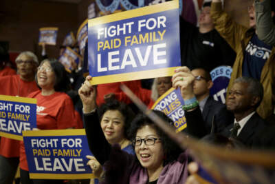 People hold signs and listen to speakers during a rally for paid family leave in New York, Thursday, March 10, 2016. (Seth Wenig/AP)
