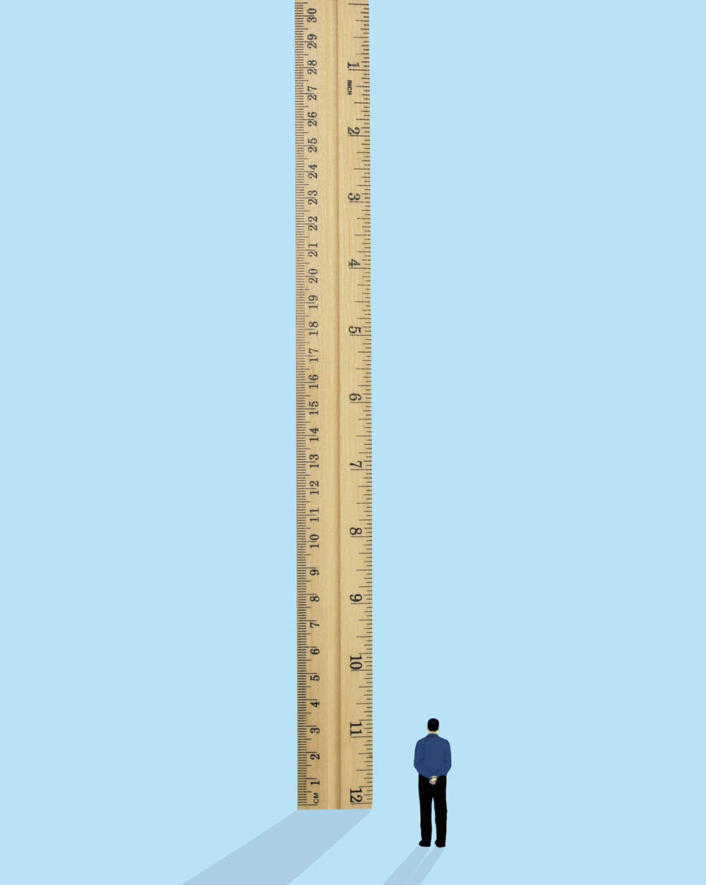 Man standing near oversized ruler against blue background. (Getty)