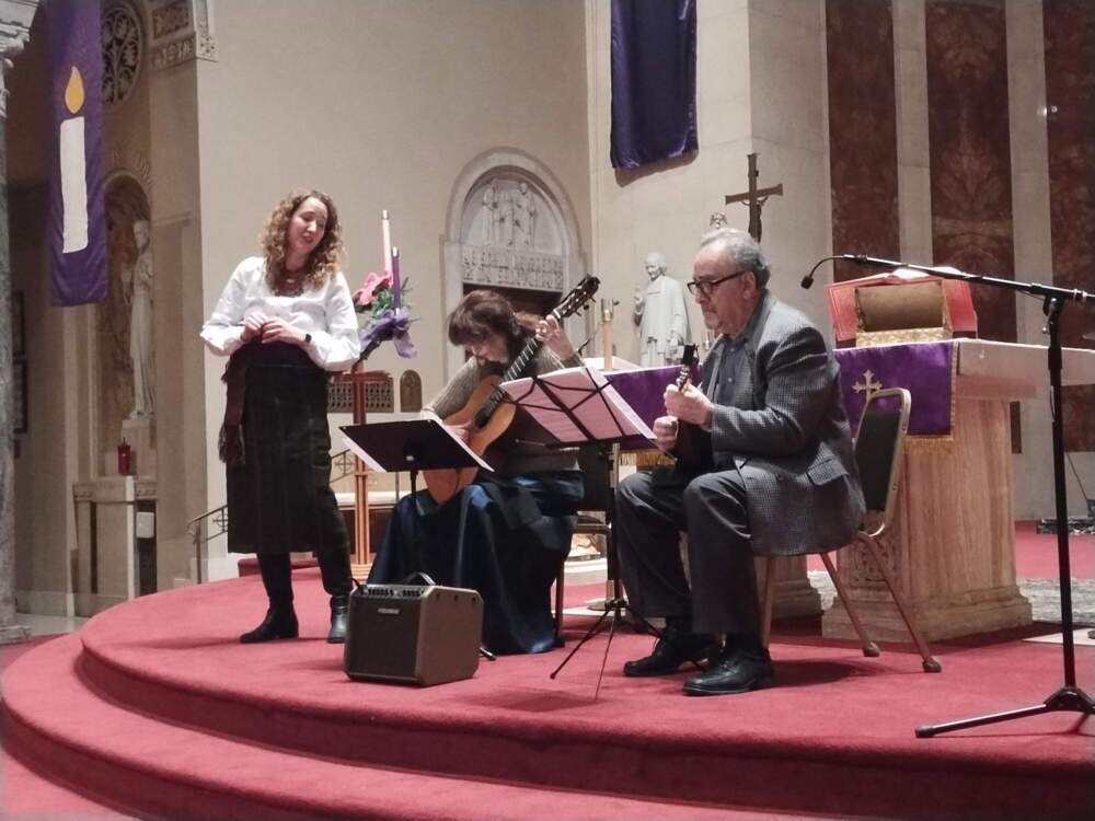 Krystia Nora sings as Irina Yanvoska plays guitar and Mikhael Litvin performs on mandolin, at a December benefit concert for wounded Ukrainian soldiers. The concert was held at St. Robert Roman Catholic Church in Shorewood, Wisconsin. (Chuck Quirmbach/WUWM)