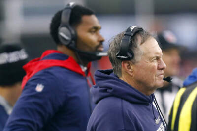 Former New England Patriots head coach Bill Belichick, right, and incoming head coach Jerod Mayo, rear left, watch from the sideline during an NFL football game. (Paul Connors/AP)
