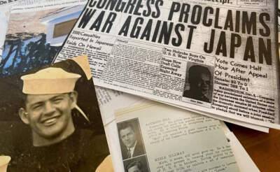 A photo of Merle Hillman, who died in the attack at Pearl Harbor, and clippings from that day on Cheryl Quinn’s kitchen table in Holyoke, Massachusetts. (Karen Brown/NEPM)