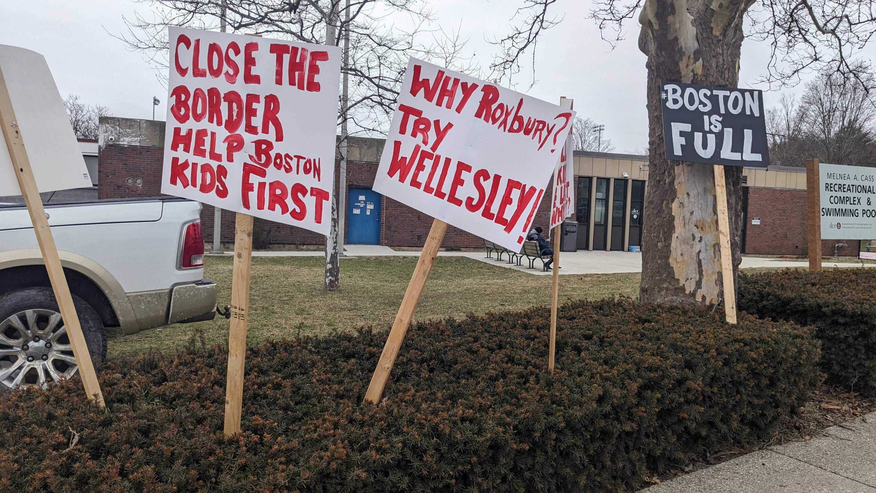 Protesters' signs outside the Roxbury recreation center, which will shelter homeless migrants until the end of May (Paula Moura/WBUR)