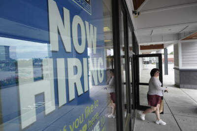 A woman passes a hiring sign in front of a store in Attleboro, Massachusetts. (Steven Senne/AP)