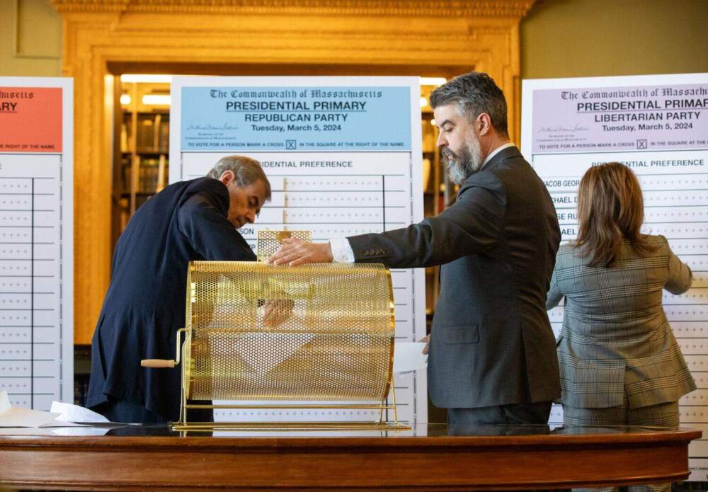 Secretary of State William Galvin draws a candidate from a golden tombola in the State Library on Tuesday, Jan. 2, 2024, assisted by William Rosenberry of the Elections Division, as he determines the order of names on the Super Tuesday presidential primary ballots. (Sam Doran/State House News Service)