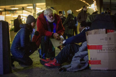 During Boston's annual homeless census, Mayor Michelle Wu and Jim Greene, the city's assistant director of street homelessness initiatives, talk with a man who's spending the night next to the Old State House. (Robin Lubbock/WBUR)