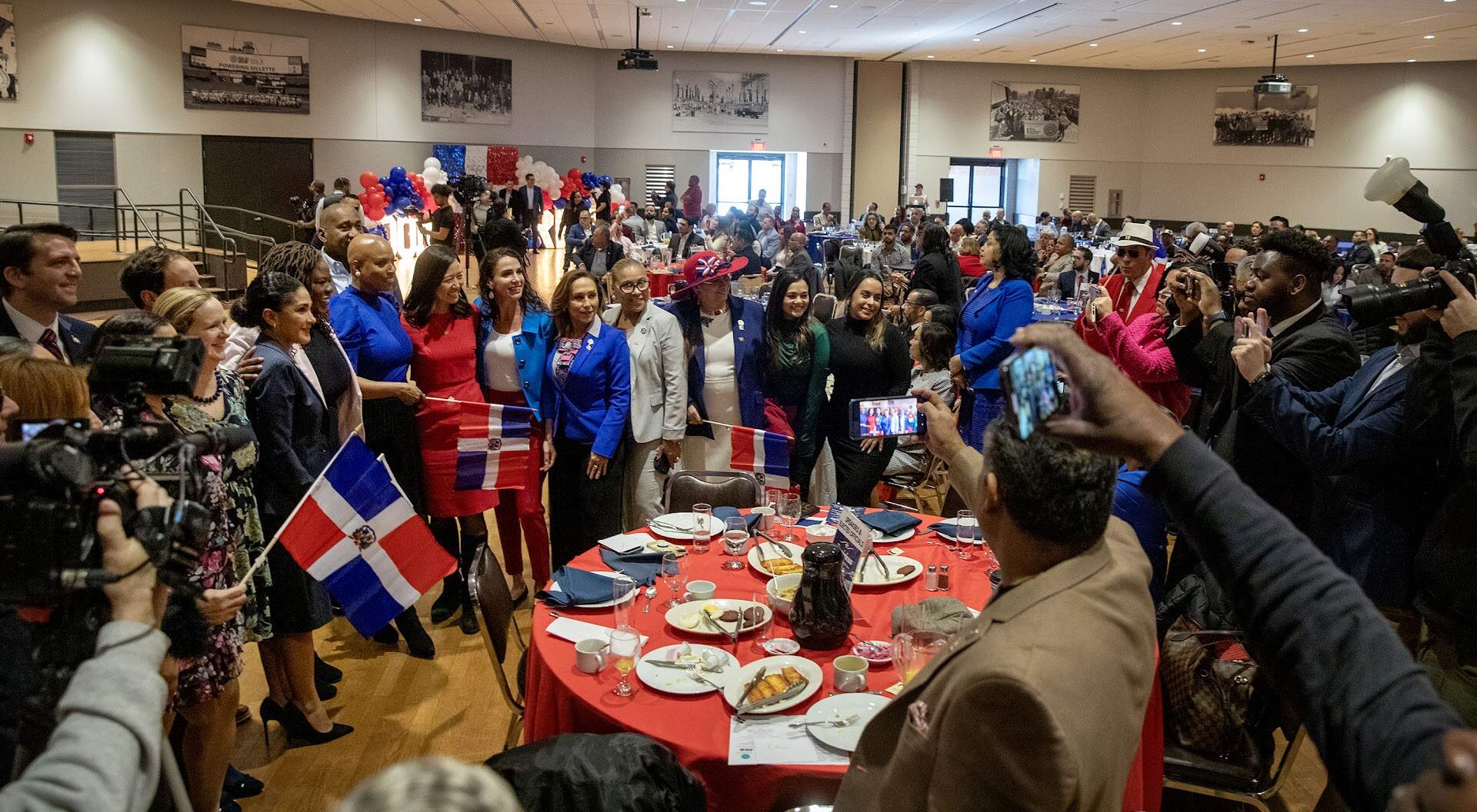 Elected officials and guests gather round Rep. Ayanna Pressley and Mayor Michelle Wu for a photo at the First Annual Dominican Independence Day Breakfast in Boston. (Robin Lubbock/WBUR)