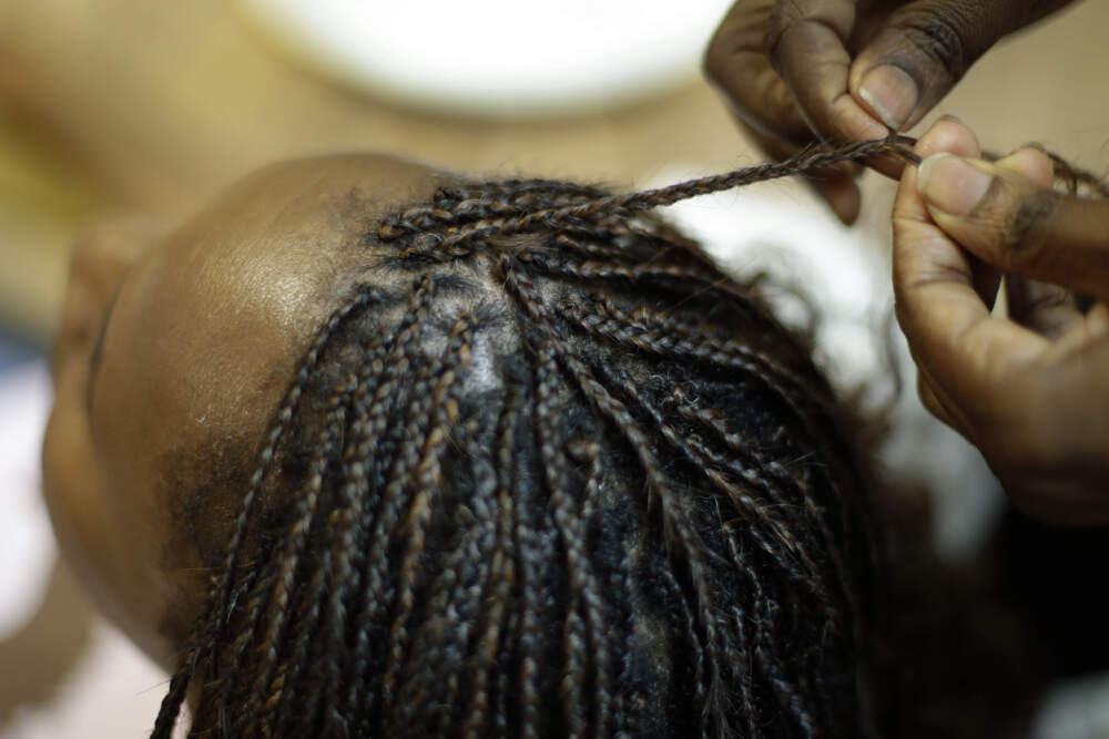 A woman gets her hair braided. (Charlie Riedel/AP)