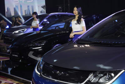Models stand near BYD electric cars on display. (Achmad Ibrahim/AP)