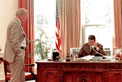 U.S. Secretary of State George P Shultz (left) watches as U.S. President Ronald Reagan speaks on the telephone in the White House's Oval Office, Washington DC, August 12, 1982. (Mary Anne Fackelman/White House via CNP/Getty Images)
