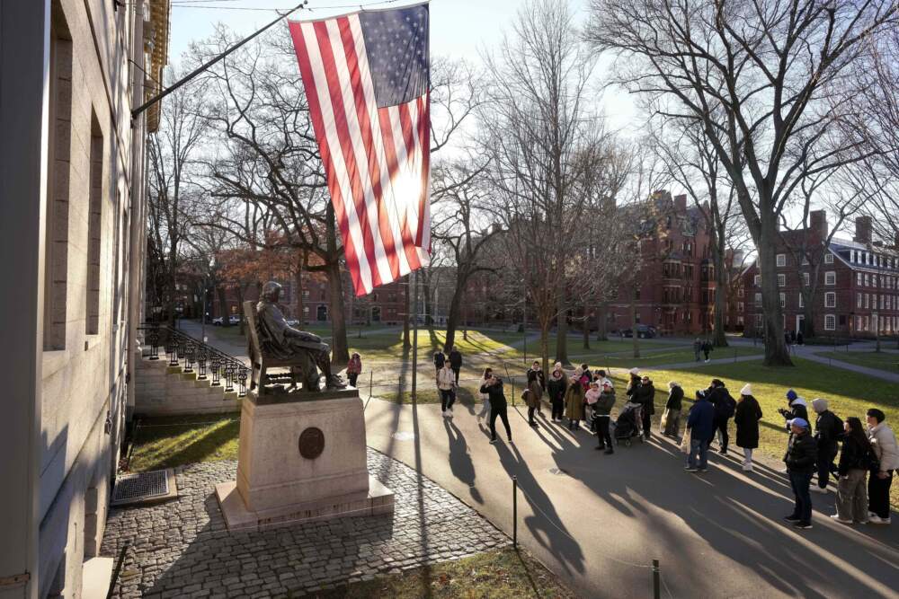 People take photos near a John Harvard statue, left, on the Harvard University campus, Jan. 2, 2024, in Cambridge, Mass. (Steven Senne/AP)