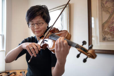 Violinist Clara Kim plays a Giovanni Battista Guadagnini violin made in Turin in 1783, at Reuning & Son Violins, as she make her selection of a fine violin for A Far Cry's &quot;Stradivari Serenade.&quot; (Robin Lubbock/WBUR)