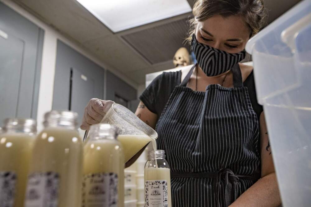 Brit McMahan, manager for the Boston restaurant Drink, fills bottles with piña colada for takeout in 2020. (Jesse Costa/WBUR)