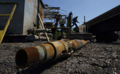 An oil well worker moves equipment at a site on the Rooke family ranch where an orphaned well was plugged. (Eric Gay/AP)