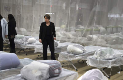 Gov. Maura Healey pauses to look at cots during a tour in January of a temporary shelter in the Melnea A. Cass Recreational Complex in Boston. (John Tlumacki/The Boston Globe, pool via AP)