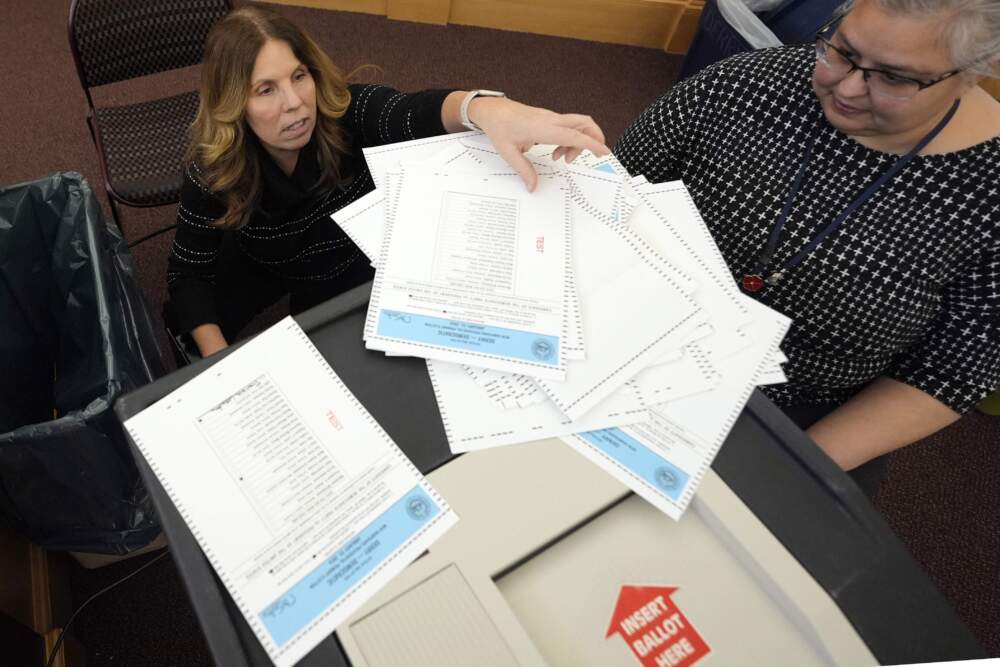 Lynne Gagnon, deputy town clerk in Derry, New Hampshire, unloads test ballots from a storage cart as Tina Guilford, Derry town clerk, prepares to load them into the ballot counting machine again while testing the machines ahead of the New Hampshire primary Jan. 16, 2024. (Charles Krupa/AP)