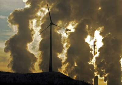 A wind turbine is pictured in the in front of a steaming coal power plant in Gelsenkirchen, Germany. (Martin Meissner/AP)