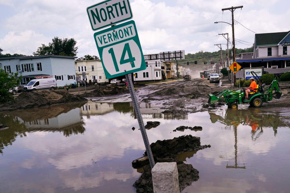 A small tractor clears water from a business as flood waters block a street, July 12, 2023, in Barre, Vt. (Charles Krupa/AP)