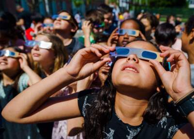 Pupils, wearing protective glasses, look at the partial solar eclipse in Schiedam, Netherlands, on June 10, 2021. (Marco de Swart/AFP via Getty Images)