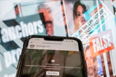 This photo illustration created in Washington, DC, on November 17, 2023, shows a phone screen showing a social media video marked as an &quot;altered video,&quot; in front of a fact-checked image of news anchors where the claim about them was found to be false. (STEFANI REYNOLDS/AFP via Getty Images)