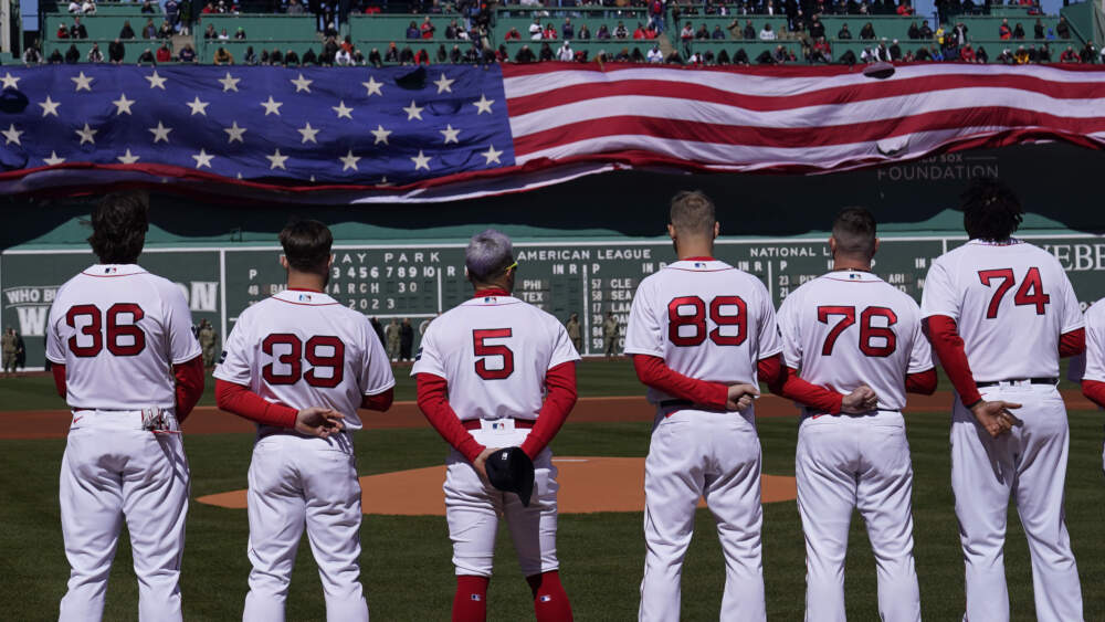 Boston Red Sox players stand for the national anthem as a giant flag is unfurled prior to an opening day baseball game against the Baltimore Orioles, Thursday, March 30, 2023, in Boston. (Charles Krupa/AP)