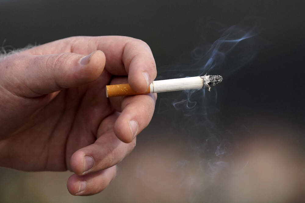 A man holds a lit cigarette while smoking. (Jeff Chiu/AP)
