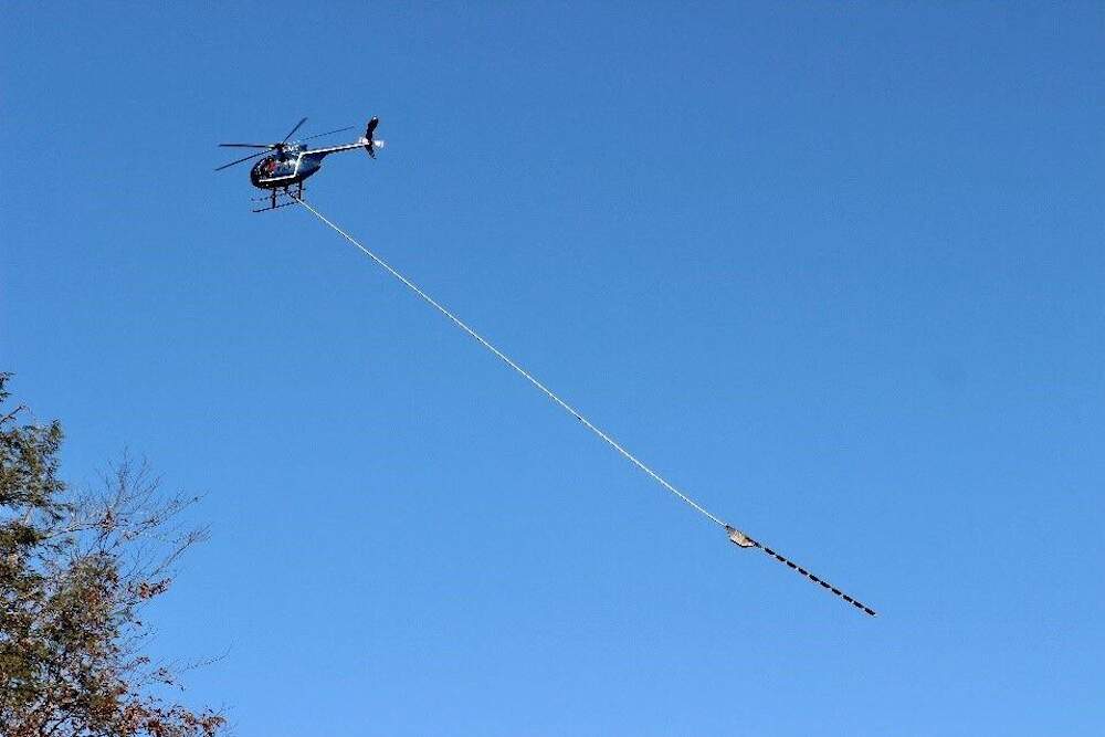 Eversource will employ a helicopter suspending a 10-bladed saw to trim tree limbs near transmission lines. (Photo courtesy Eversource via State House News Service)
