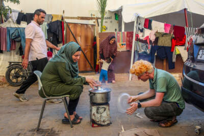 Wisal Abu Odeh and her husband cooking near their tent at a makeshift U.N. camp for displaced Palestinians in Khan Younis. (Samar Abu Elouf/New York Times)