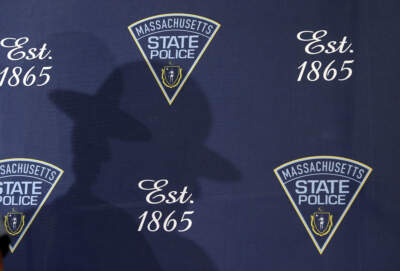 A state police trooper casts a shadow on a backdrop during a press conference in Framingham in 2019. (Jessica Rinaldi/The Boston Globe via Getty Images)