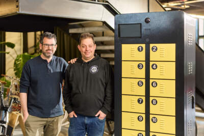 PopWheels co-founders David Hammer and Baruch Herzfeld next to a charging cabinet. (Courtesy of Urban X)