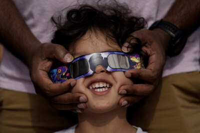 Viewers use special glasses to watch as the moon moves in front of the sun. (Eric Gay/AP)
