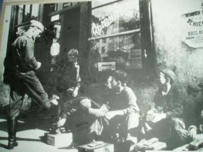 A photo of a photo, taken by the author at the The Belarusian Museum on a research trip to Belarus in 2006. The image shows a Nazi soldier getting his boots shined by boys like the author's father during the occupation of Minsk. (Courtesy Jason Prokowiew)