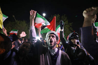 Demonstrators wave Iran's flag and Palestinian flags as they gather in front of the British Embassy in Tehran on April 14, 2024, after Iran launched a drone and missile attack on Israel. (Atta Kenare/AFP via Getty Images)