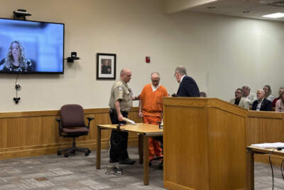 Barry Cadden, center, enters court in Livingston County, Mich., Thursday, April 18, 2024. Cadden operated New England Compounding Center, a Massachusetts specialty pharmacy, which caused a national meningitis outbreak in 2012. On Thursday, the involuntary manslaughter sentencing for Cadden was suddenly postponed when lawyers looked up and saw a different judge on the bench. (Ed White/AP)