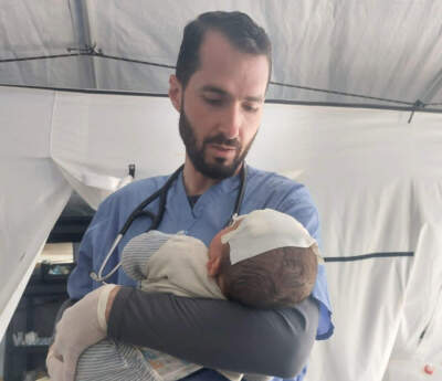 Dr. Mohammad Subeh in Gaza holding a baby with a head trauma after a missile strike. She came in without parents and was brought in by someone who found her. (Courtesy of Mohammad Subeh)