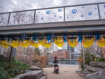 A walkway in Martin's Park overlooking Fort Point Channel is decorated with Boston Marathon blue and yellow, and peace signs in honor of Martin Richard. (Sharon Brody/WBUR)