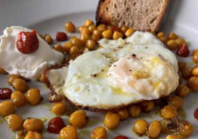Olive oil-fried eggs with spiced roasted chickpeas, harissa and sour cream. (Kathy Gunst/Here & Now)