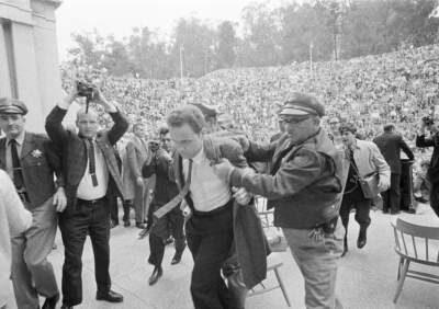 Mario Savio, leader of the Berkeley Free Speech Movement, is restrained by police as he walks on to the platform at the University of California's Greek Theater in Berkeley. (Robert W. Klein/AP)