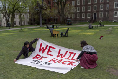 Demonstrators unfurl a banner on a lawn after an encampment protesting the Israel-Hamas war was taken down at Brown University, Tuesday, April 30, 2024, in Providence, R.I. Brown University administrators and leaders of several student groups on Tuesday said a deal would end a protest there by evening. The statements said President Christina Paxson had committed to an October vote by the school's governing board on the students' divestment proposal. (David Goldman/AP)